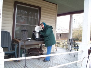 Barbara cooking on the camping stove while standing on the porch.