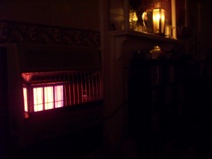 The glow of a wall mounted propane heater and an enclosed candle lantern in the dark of the night.